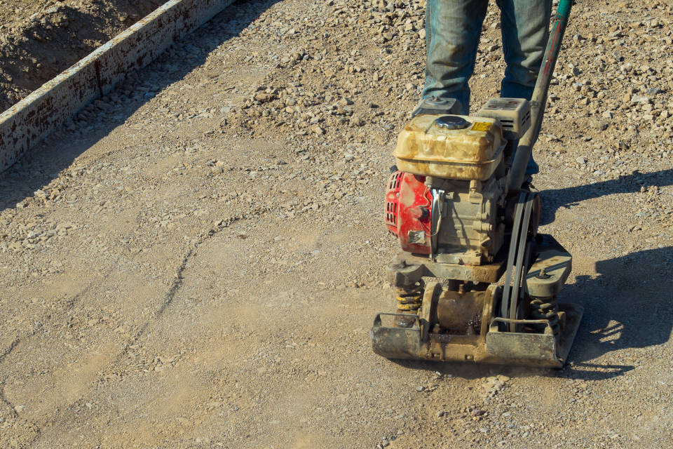 compacting the gravel patio base using a plate compactor